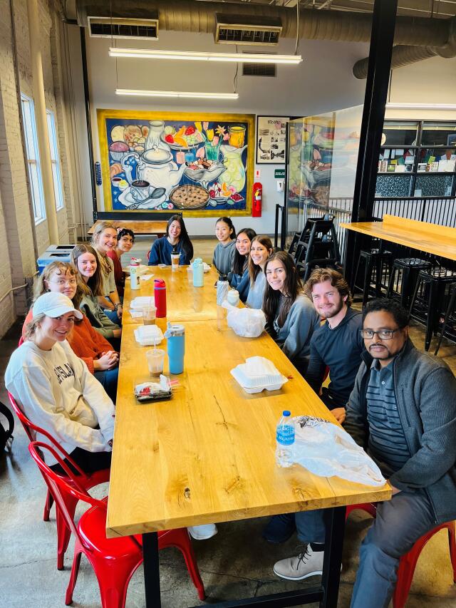 A faculty mentor sits with their cohort for lunch at the North Market